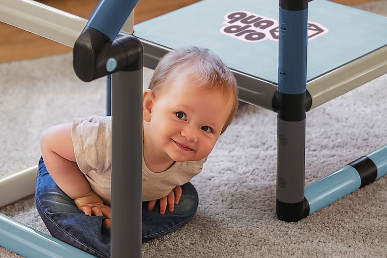 Child peaking from behind a small climbing frame and play house